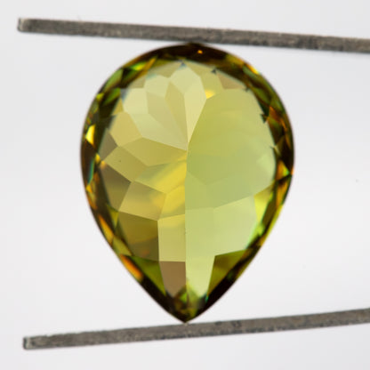 Pavilion-side view of the pear-shaped sphene in tweezers, showing broad pale-yellow facets.
