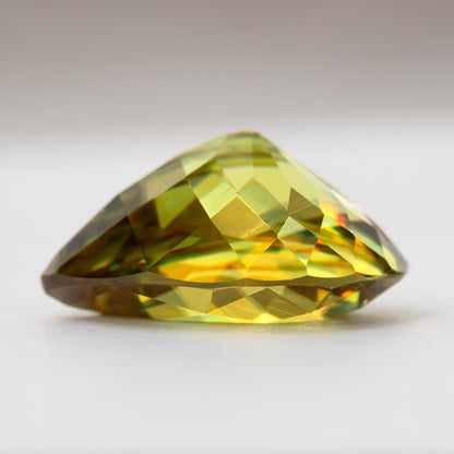 Side profile of the pear-shaped sphene showing crown and pavilion height on a white surface.