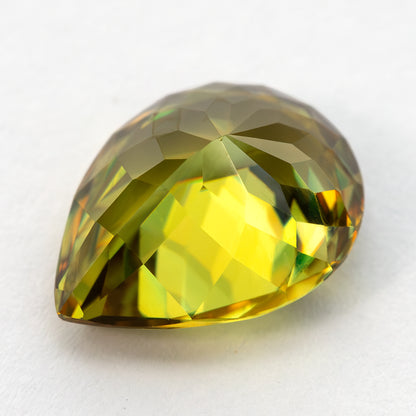 Angled side view of the green-yellow sphene showing its pavilion and curved pear outline.