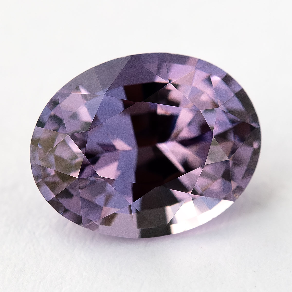 Mauve lavender oval spinel face-up on a pale background.