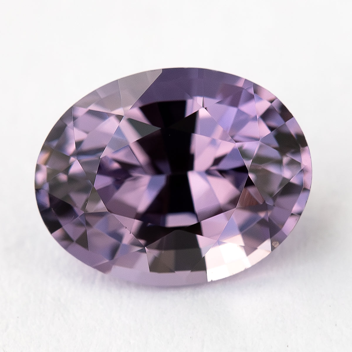 Oval lavender-pink spinel lying face-up with alternating bright and dark reflections.