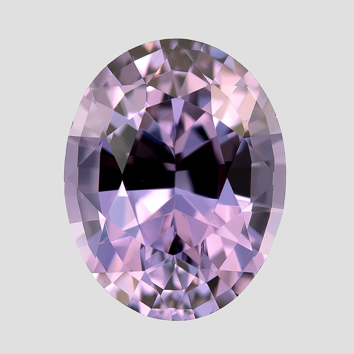 Oval spinel lying face-up in a vertical orientation on a pale surface.