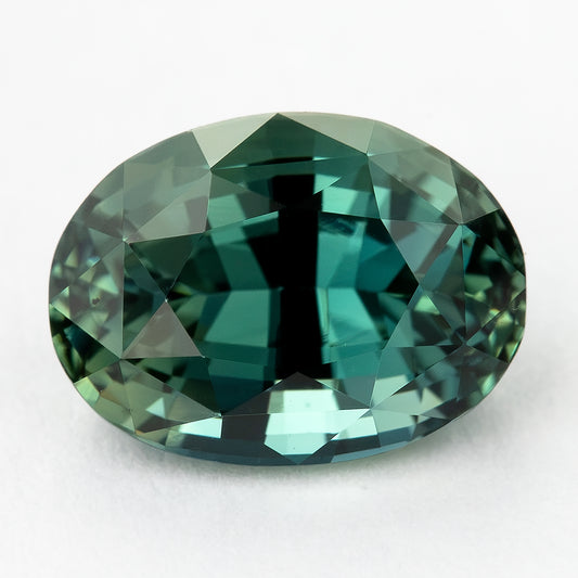 Face-up view of the 2.27 ct oval teal sapphire, showing its green-blue colour, oval outline and mixed-cut facet pattern in natural daylight.