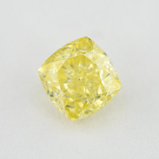 Face-up cushion-shaped yellow diamond on a pale surface, showing its complete outline, table and crown facets.