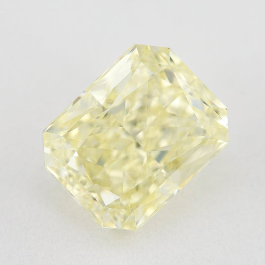 Face-up view of a pale yellow rectangular radiant-cut natural diamond on a pale surface, showing its complete outline and crown facets.