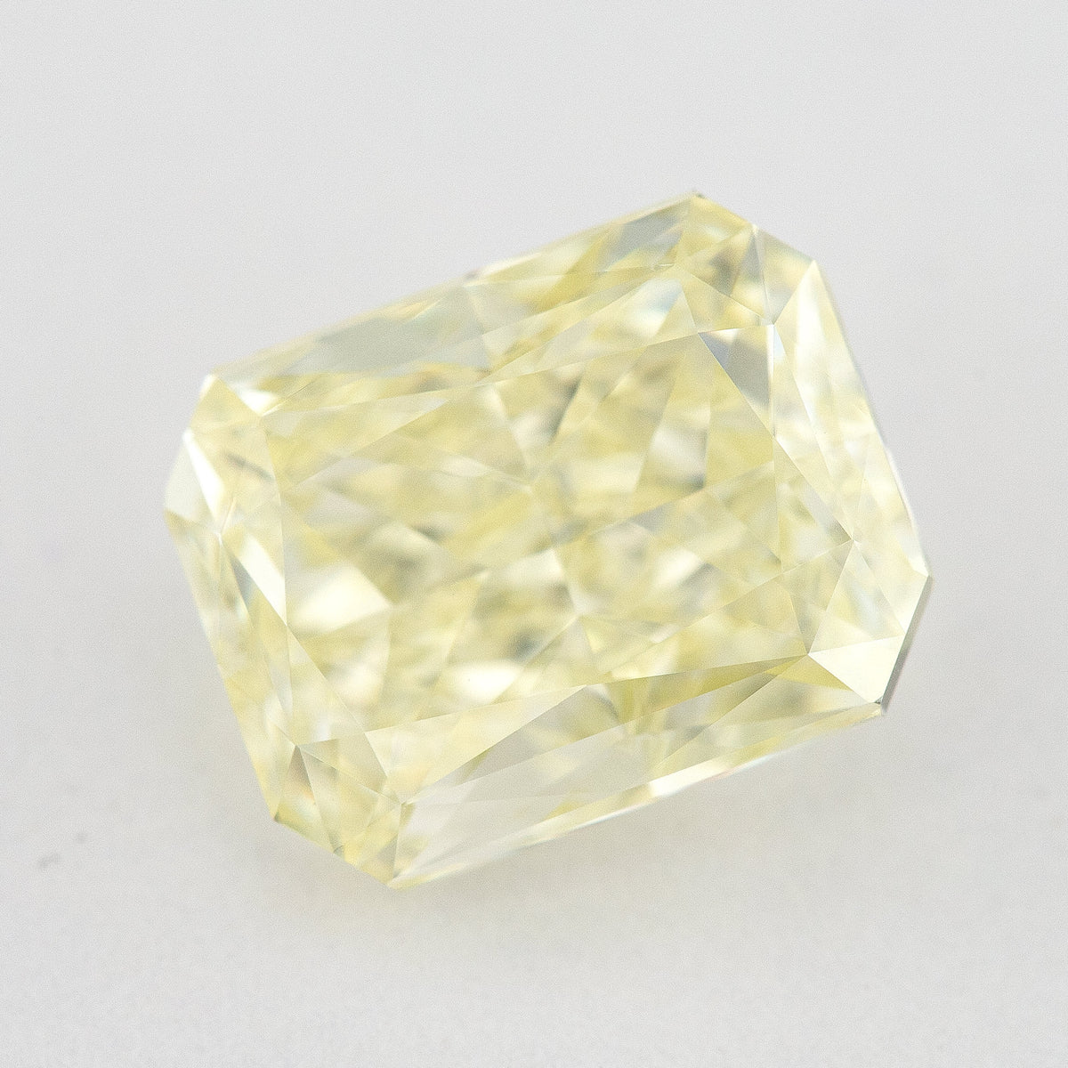 Tilted crown view of the pale yellow rectangular radiant-cut natural diamond, showing a different pattern of bright and dark facet reflections.