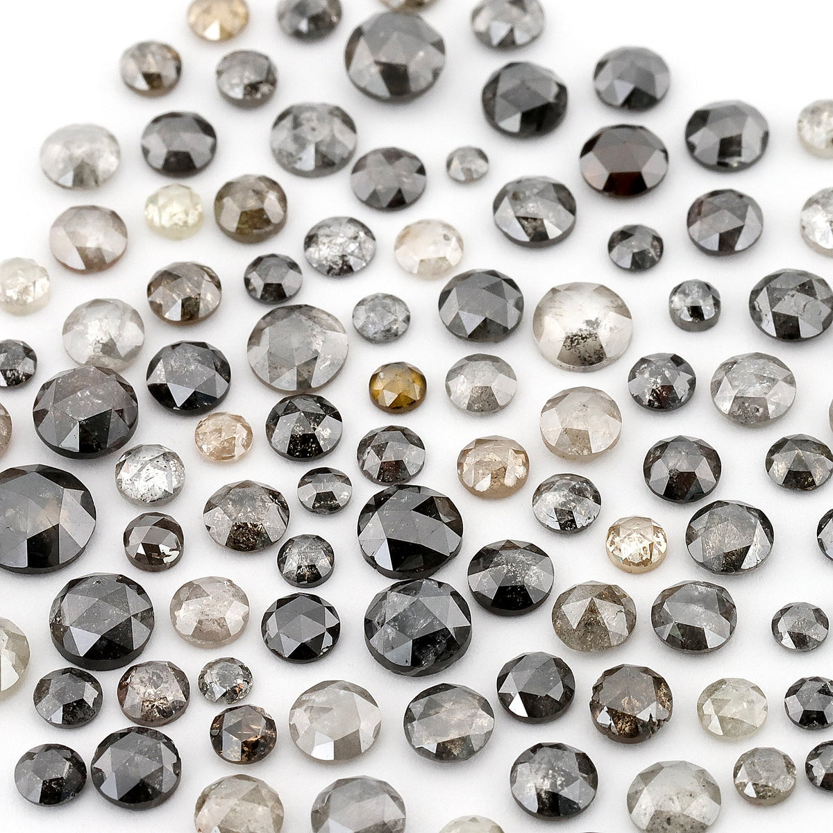Assorted round rose-cut diamonds in pale grey, dark grey and black on white; this shows the source parcel, not a promised individual scoop.