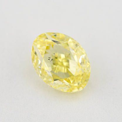 Oval yellow diamond rotated on a pale background, showing a different face-up reflection and visible inclusions.