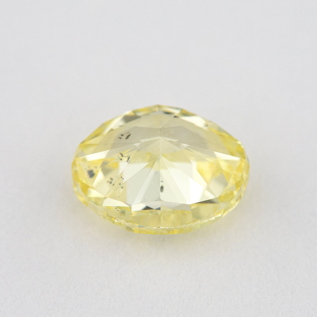 Back and pavilion view of the oval yellow diamond, with inclusions visible through broad facets.