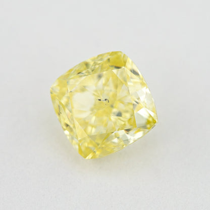 Angled crown view of the cushion-shaped yellow diamond, showing brighter reflections and small dark central marks.