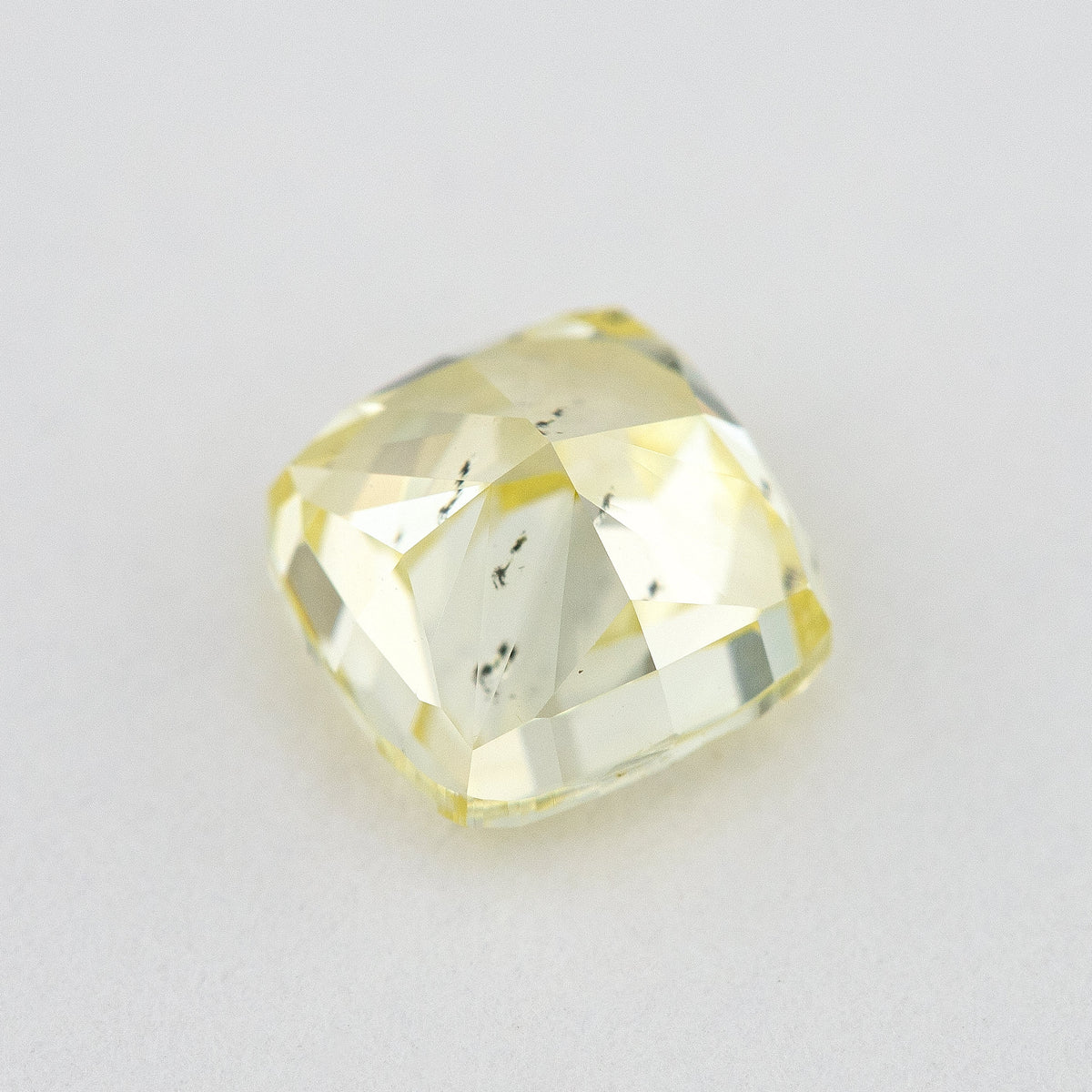 Pavilion and back view of the cushion-shaped yellow diamond, with broad rear facets and dark marks visible within the stone.