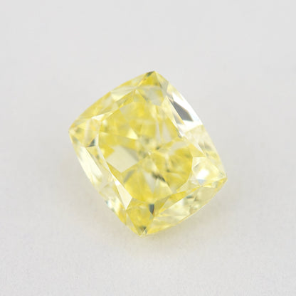 Alternate angled face-up view of the yellow cushion diamond on a pale background, with a different pattern of light and dark facet reflections.