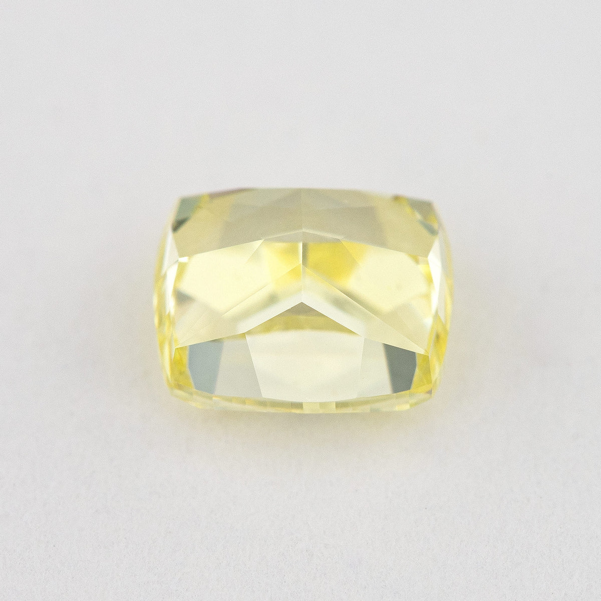 Low tilted view of the yellow cushion diamond, showing broad pavilion facets and the depth below its crown.