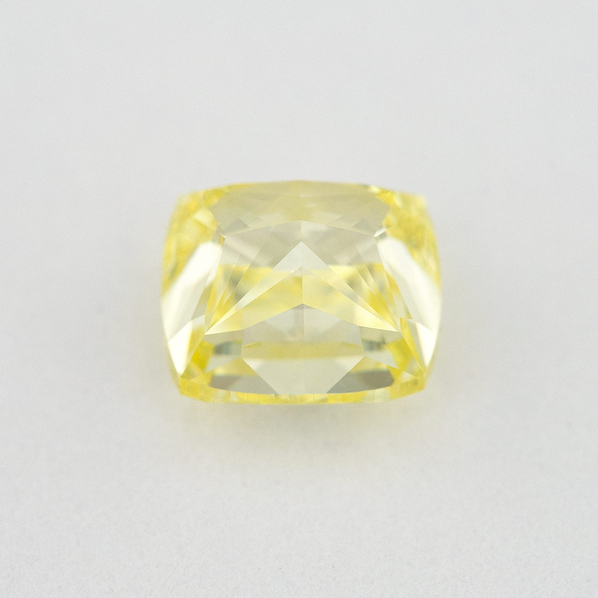 Back and pavilion view of the cushion-shaped yellow diamond on a pale background.