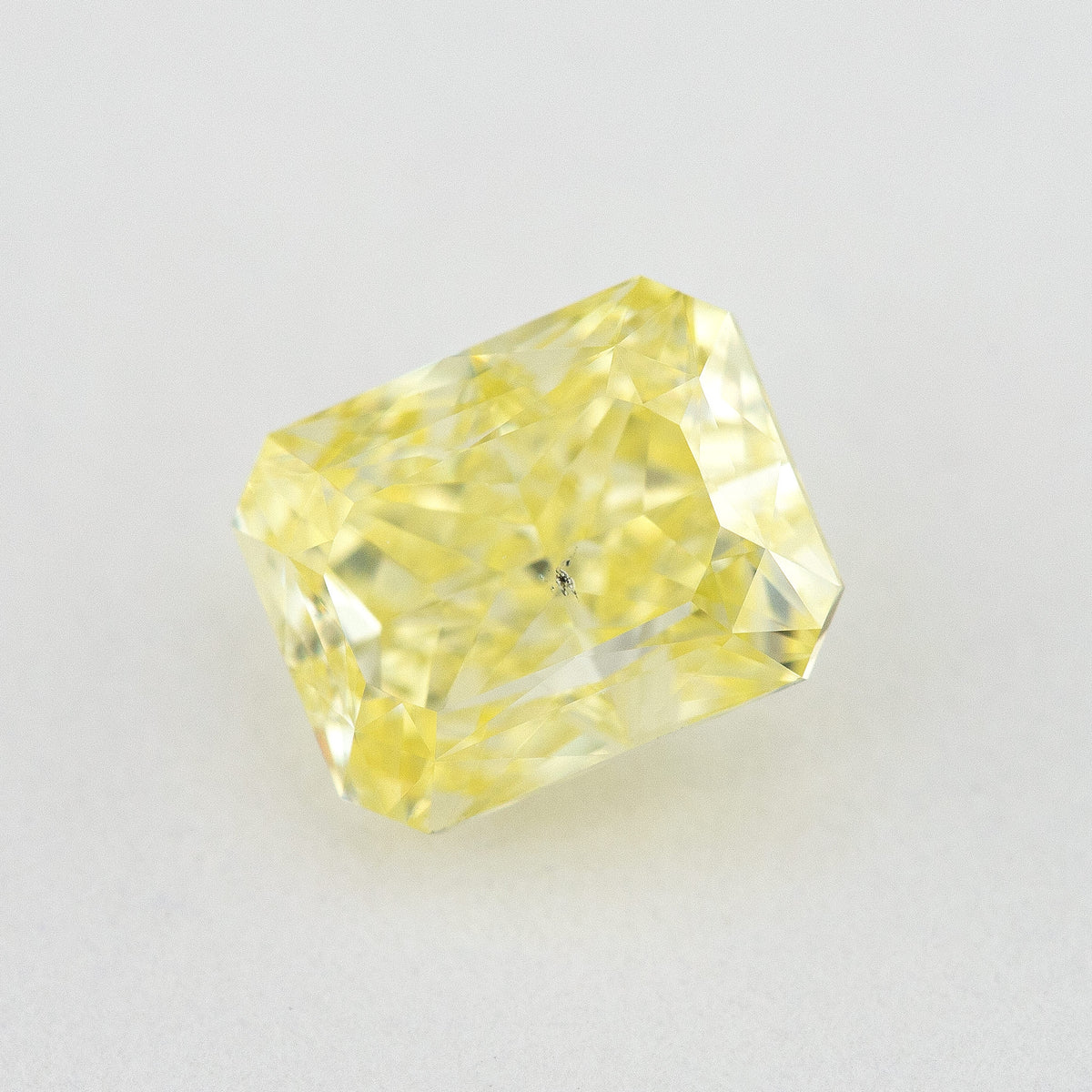Angled crown view of the radiant-cut yellow diamond, with bright reflections across its rectangular face.