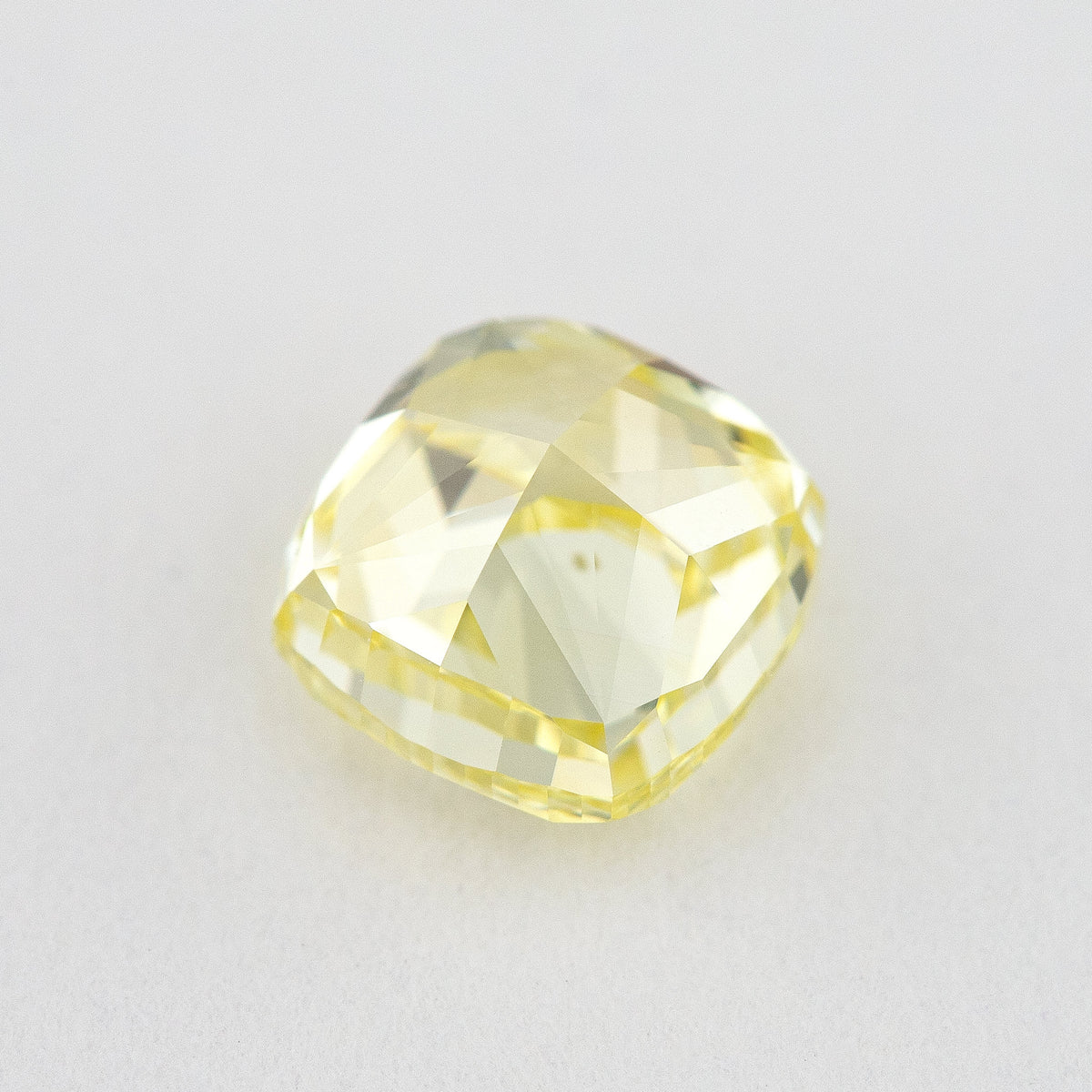 Back view of the yellow cushion diamond, showing the pavilion faceting and outline.