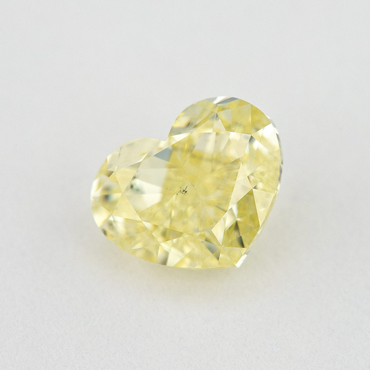 Angled crown view of the heart-shaped yellow diamond, showing its outline and a different pattern of facet reflections.