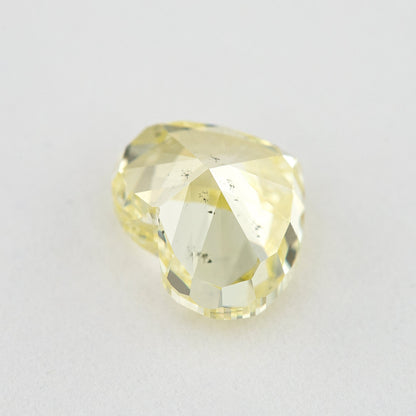 Pavilion and back view of the heart-shaped yellow diamond, showing broad rear facets and small dark marks.