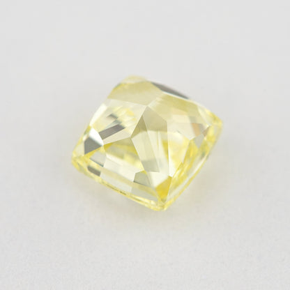 Pavilion and back view of the cushion-shaped yellow diamond, showing broad rear facets on a pale surface.