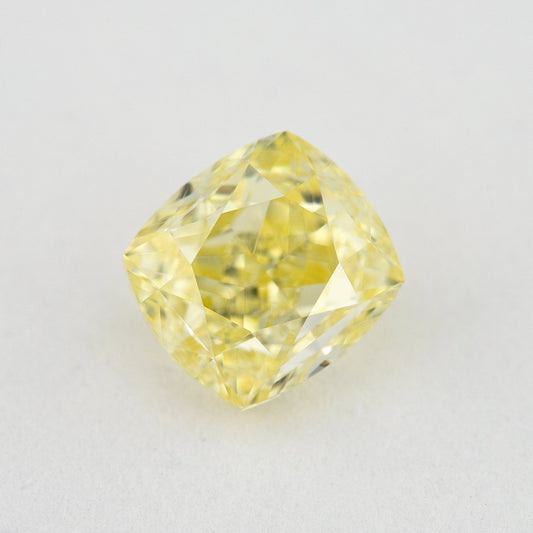 Face-up cushion-shaped yellow diamond on a pale surface, showing its complete outline, table and crown facets.