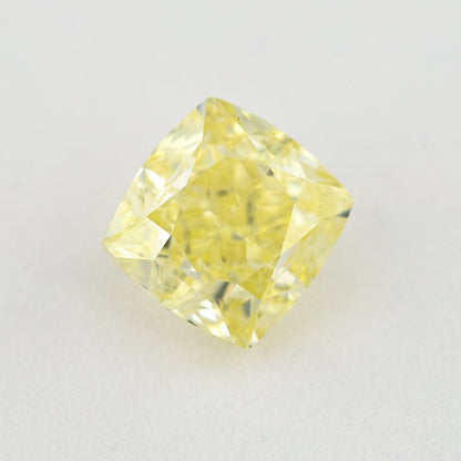 Face-up cushion-shaped yellow diamond on a pale surface, showing its complete outline, table and crown facets.