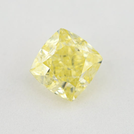Face-up cushion-shaped yellow diamond on a pale surface, showing its complete outline, table and crown facets.