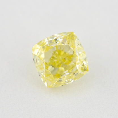 Face-up cushion-shaped yellow diamond on a pale surface, showing its outline, central table and bright crown facets.