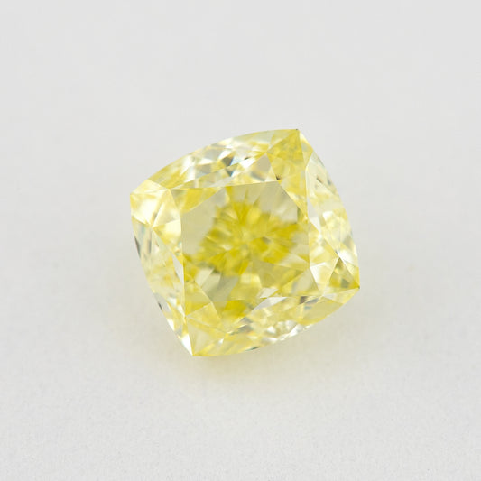 Face-up cushion-shaped yellow diamond on a pale surface, showing its outline, central table and bright crown facets.