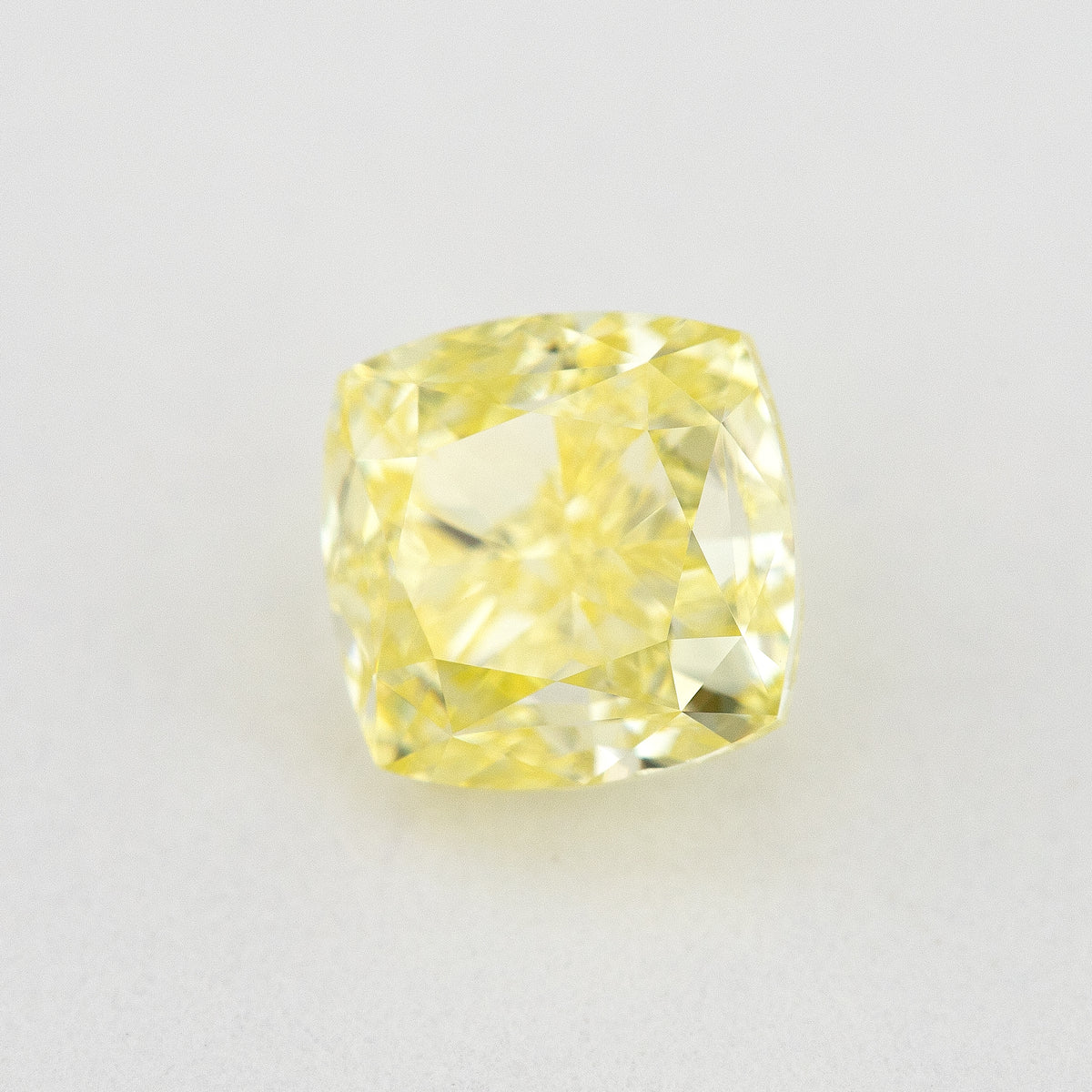 Angled crown view of the cushion-shaped yellow diamond, with a different pattern of bright and darker reflections.