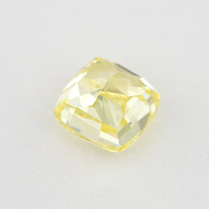 Pavilion and back view of the cushion-shaped yellow diamond on a pale surface, showing its broad rear facets.