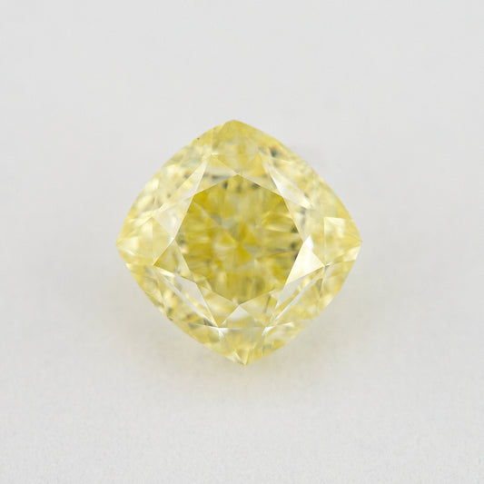 Face-up cushion-shaped yellow diamond on a pale surface, showing its complete outline, table and crown facets.