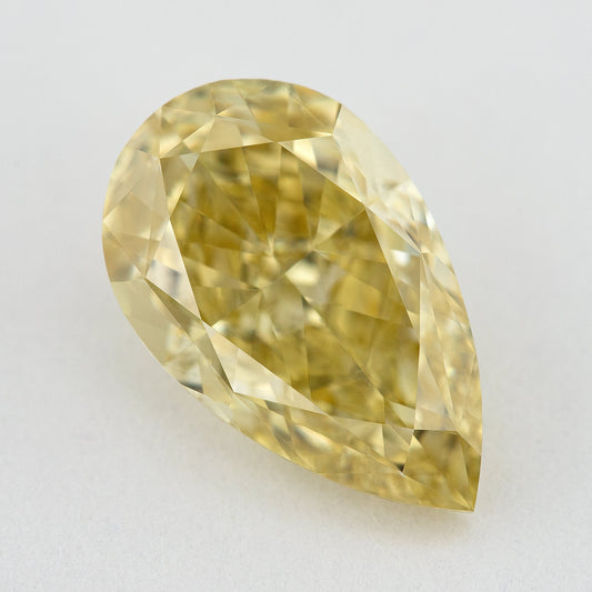 Face-up close-up of the yellow pear diamond on a pale background, showing its complete outline and crown facet reflections.