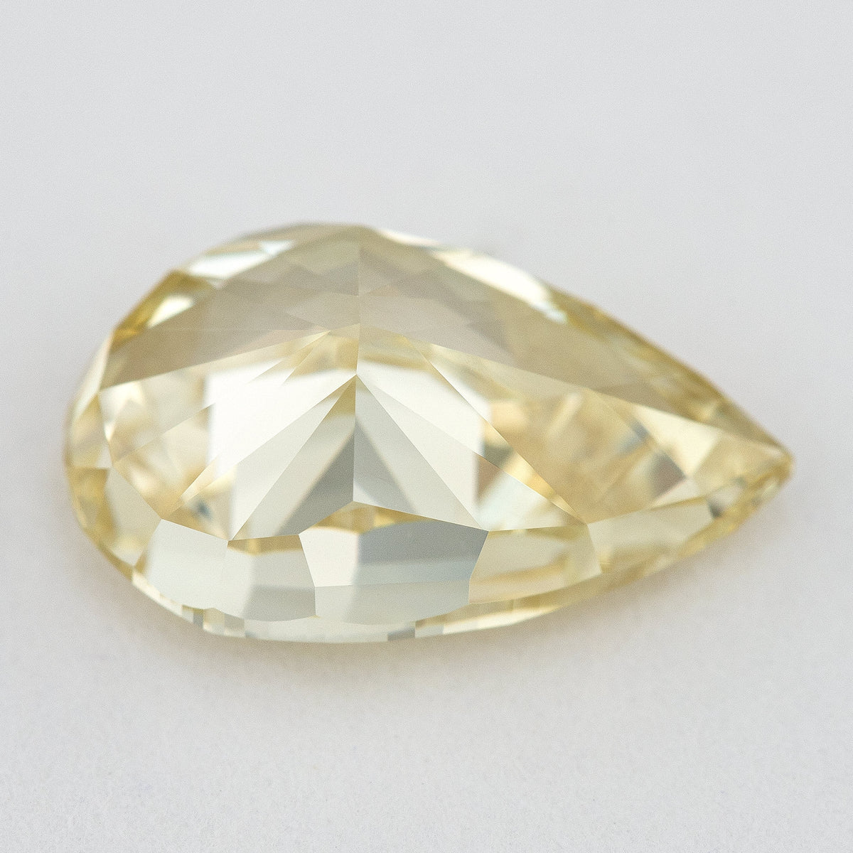 Low tilted view of the yellow pear diamond, showing broad pavilion facets and the depth below its crown.