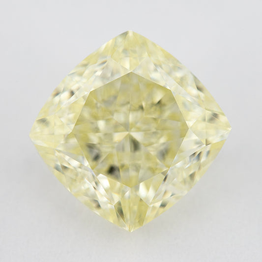 Face-up pale yellow cushion-shaped diamond on a light surface, showing its complete outline, table and crown facets.