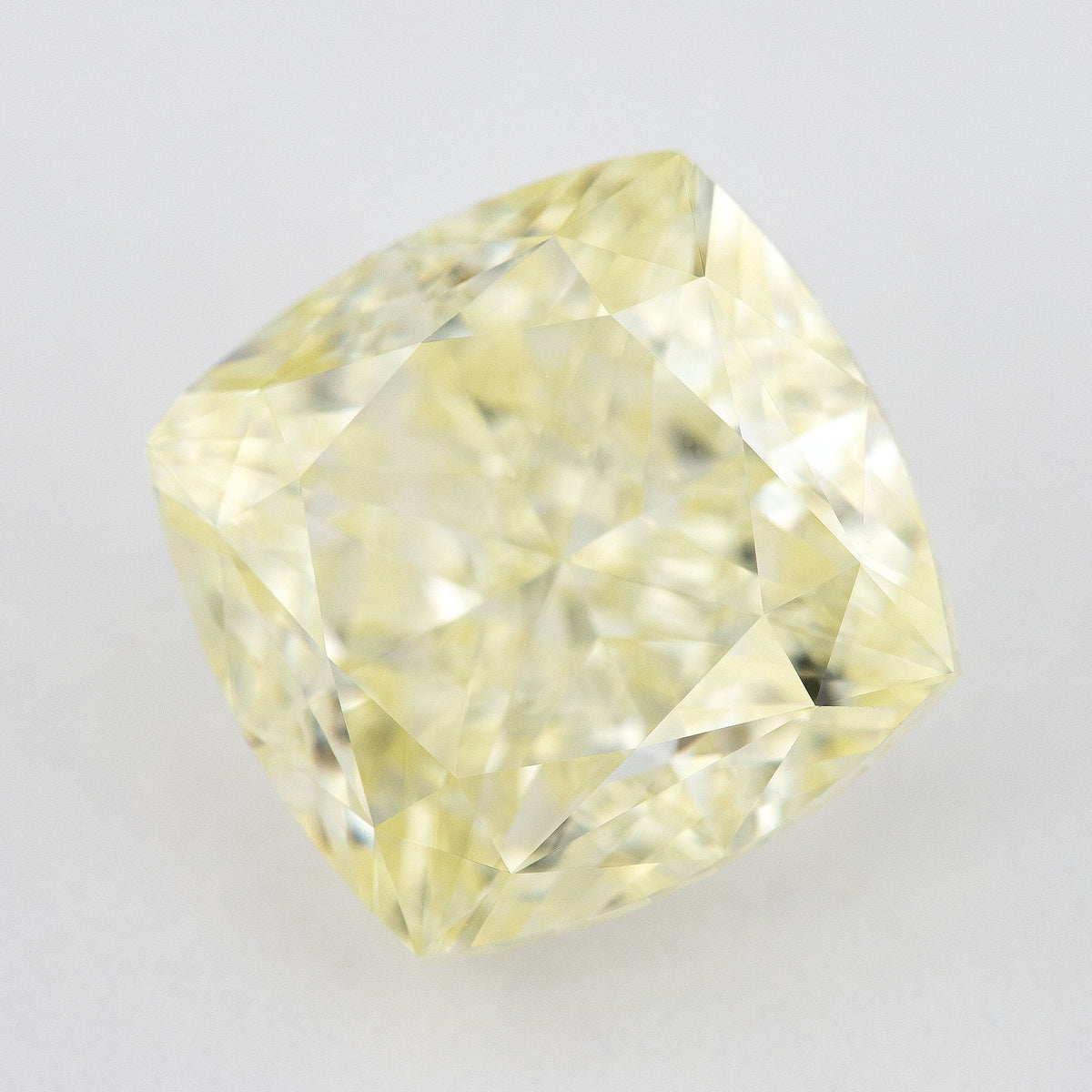 Angled crown view of the pale yellow cushion-shaped diamond, with broad bright facets and darker reflections.