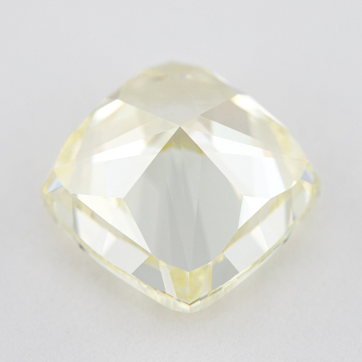 Pavilion and back view of the pale yellow cushion-shaped diamond, showing broad rear facets on a light surface.