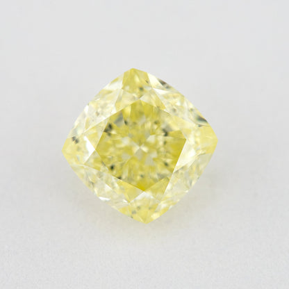 Face-up cushion-shaped yellow diamond on a pale surface, showing its complete outline, table and crown facets.
