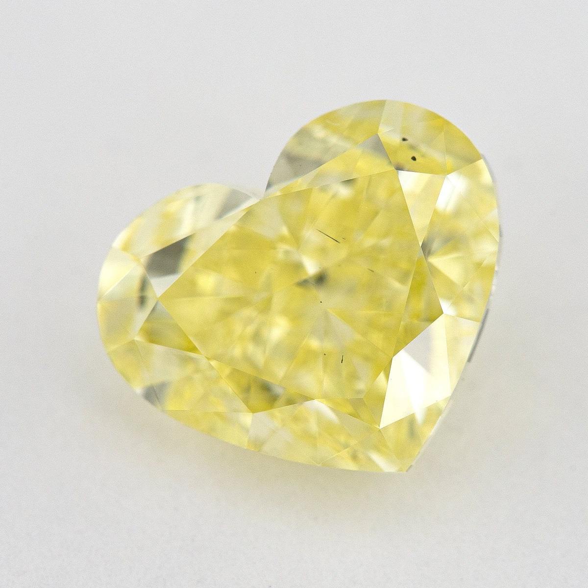 Tilted crown view of the yellow heart-shaped natural diamond, showing a different pattern of bright and dark facet reflections.