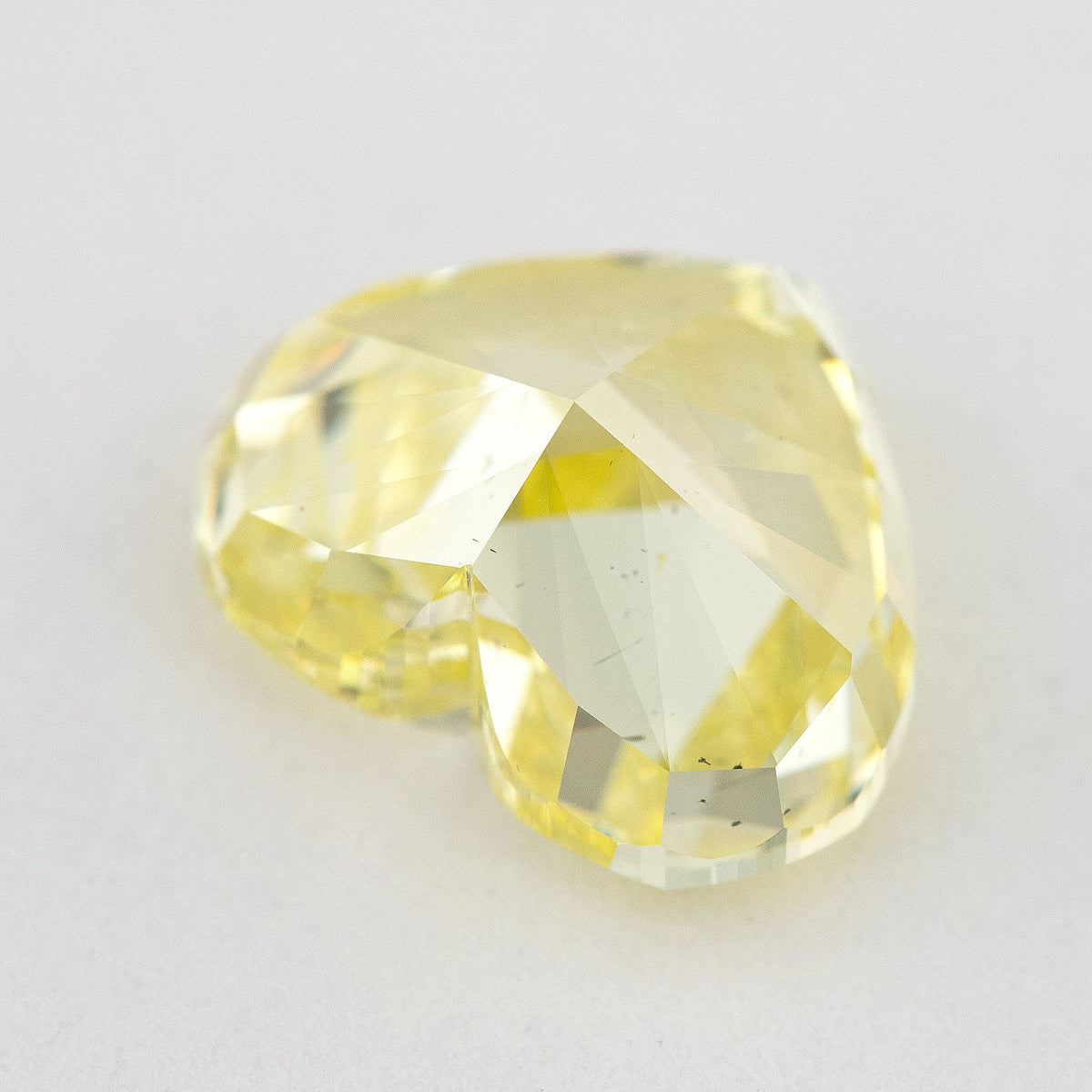 Low side view of the yellow heart-shaped natural diamond, showing the crown, girdle and pavilion facets.