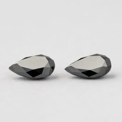 Low side view of the black pear-shaped diamonds, showing the profiles and faceted edges of both stones.