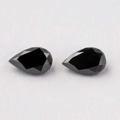 Black pear-shaped diamond pair viewed from above at a slight angle, with both pointed outlines visible.