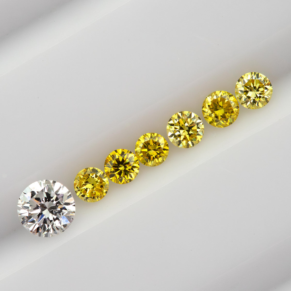 Six yellow diamonds in a diagonal face-up line beside a larger white comparison diamond, not included in the sale.