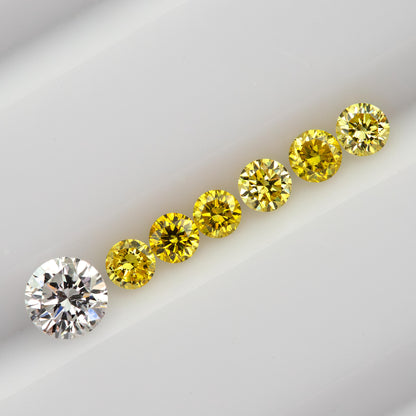 Six yellow diamonds in a diagonal face-up line beside a larger white comparison diamond, not included in the sale.