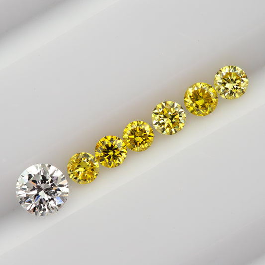 Six yellow diamonds in a diagonal face-up line beside a larger white comparison diamond, not included in the sale.