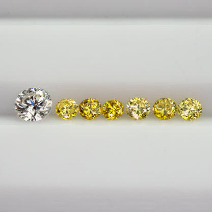 Horizontal row of six yellow diamonds on a white tray beside a white comparison diamond, not included.
