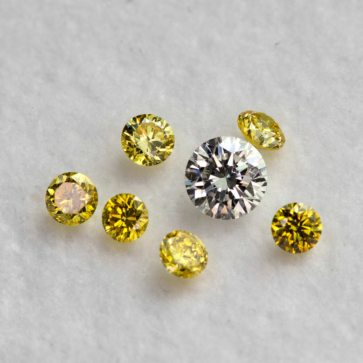 Yellow diamonds at mixed face-up and tilted angles around a white comparison diamond, not included.