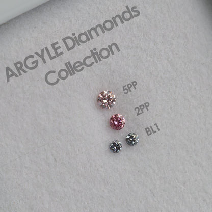 Face-up close-up of four diamonds beside printed 5PP, 2PP and BL1 merchant color labels on an ARGYLE Diamonds Collection display.
