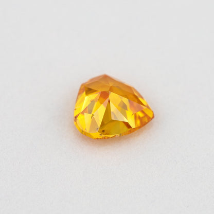 Pavilion and back view of the heart-shaped orange diamond, showing broad rear facets and orange-yellow reflections.