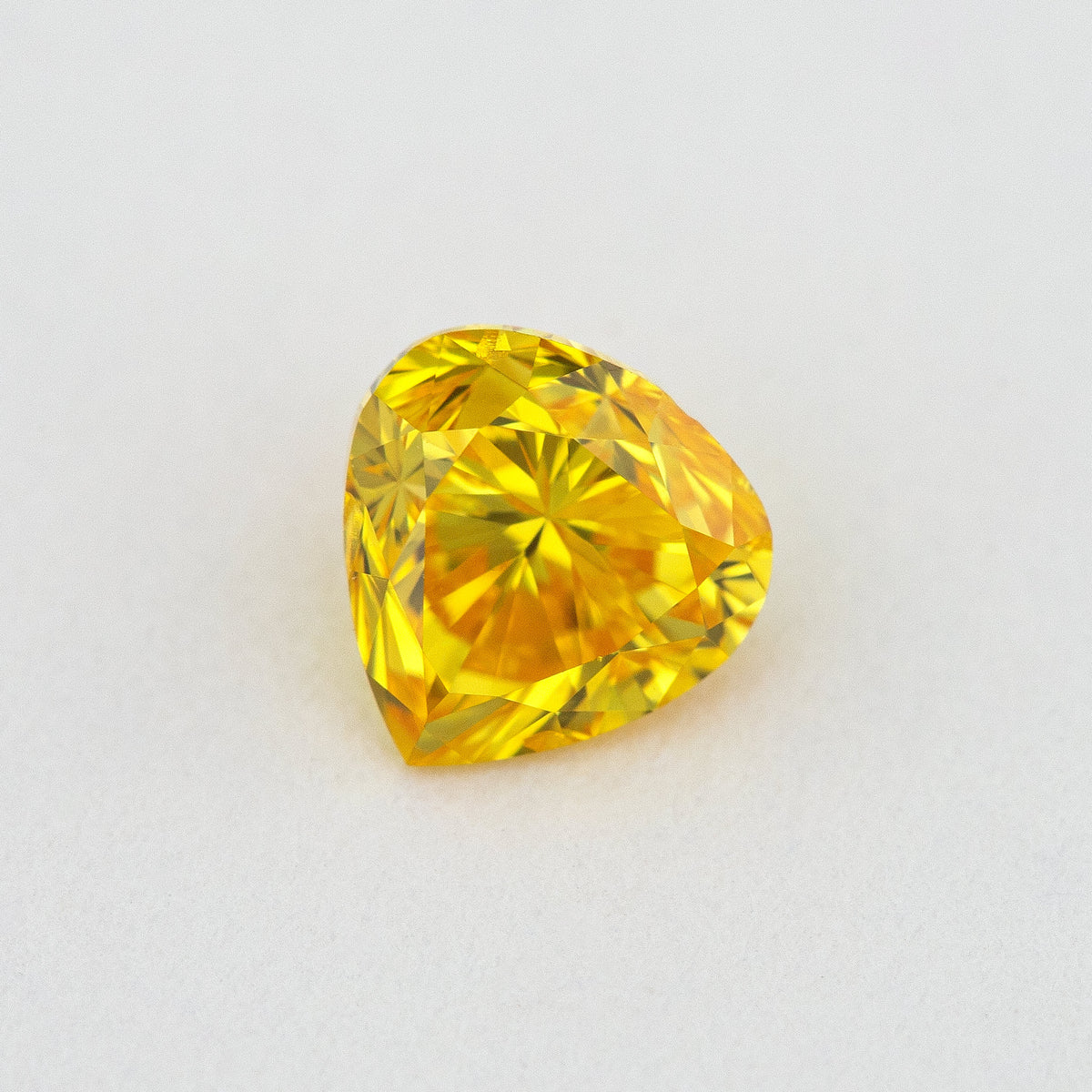 Alternate crown-side view of the yellow-orange heart-shaped diamond, showing its table and facet reflections.