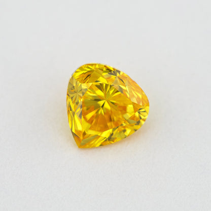 Alternate crown-side view of the yellow-orange heart-shaped diamond, showing its table and facet reflections.